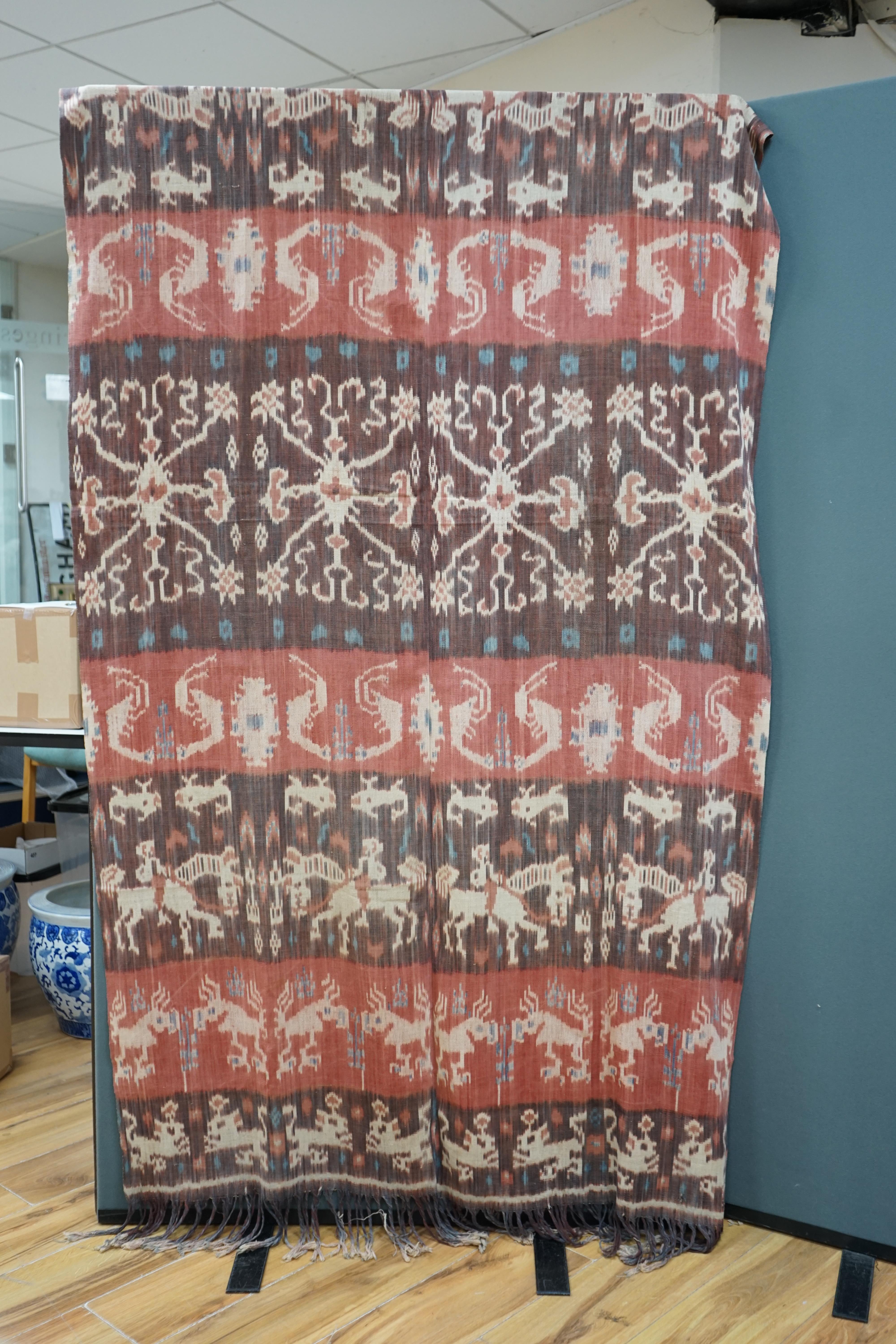 A hand woven hand dyed Ikat Sumbanese Hinggi (shoulder cloth), together with an Indian chain stitch embroidered panel, the Hinggi woven on two short 56cm wide looms sewn together forming horizontal bands, depicting men o